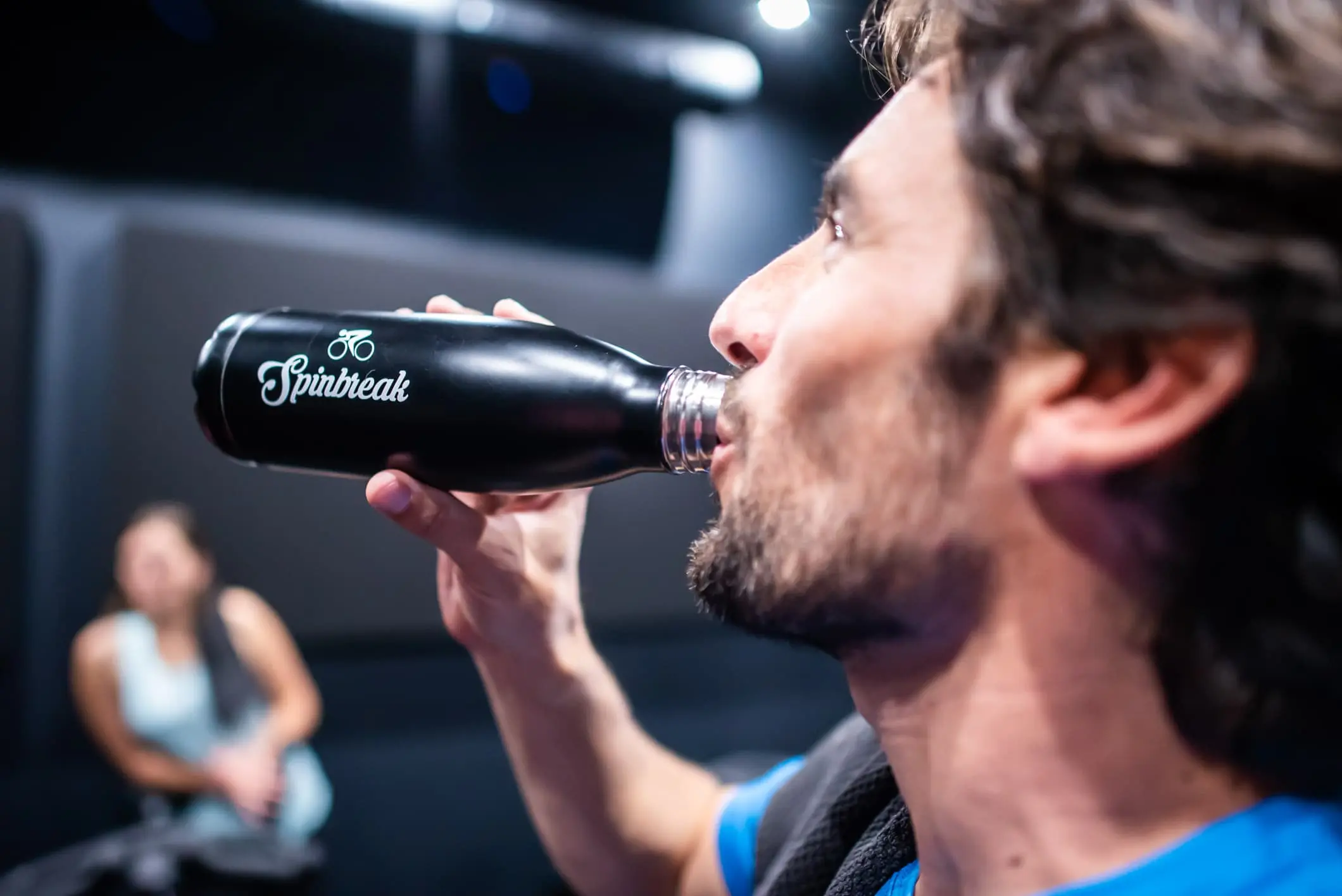 adhérent qui boit de l'eau après une séance d'indoor cycling