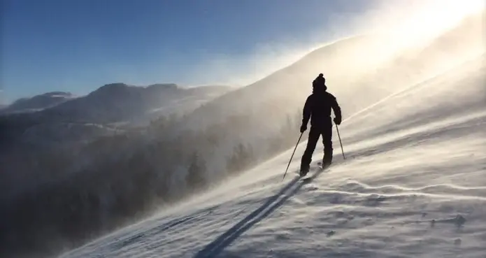 Un homme qui contemple les montagnes depuis une piste de ski
